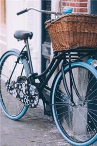 Blue Bicycle with a Wicker Basket in the City Journal