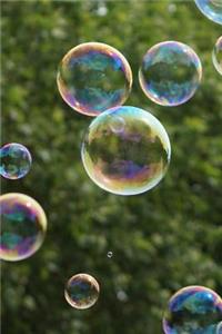 Blowing Soap Bubbles Highlighted Against Green Trees and a Blue Sky Journal